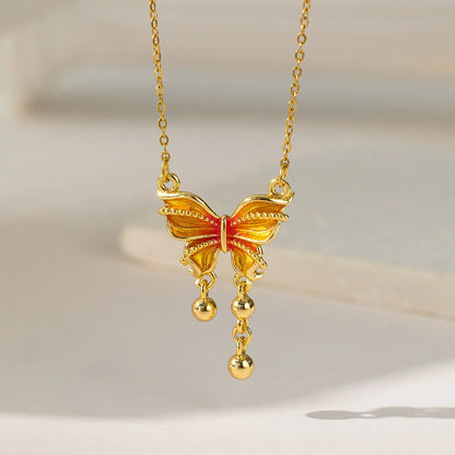 Goldene Halskette "Mira" mit orange-gelbem Schmetterlingsanhänger und kleinen goldenen Tropfen