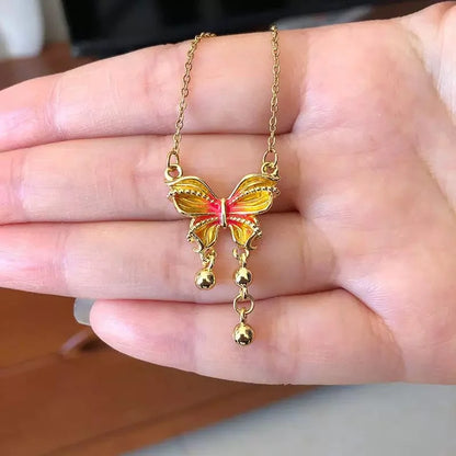 Goldene Halskette "Mira" mit orange-gelbem Schmetterlingsanhänger und kleinen goldenen Tropfen