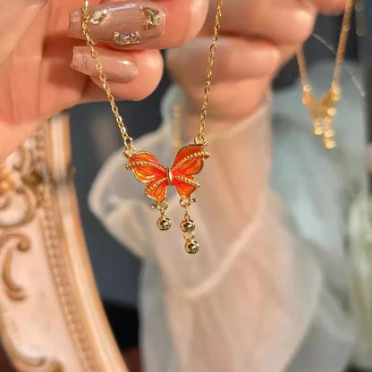 Goldene Halskette "Mira" mit orange-gelbem Schmetterlingsanhänger und kleinen goldenen Tropfen