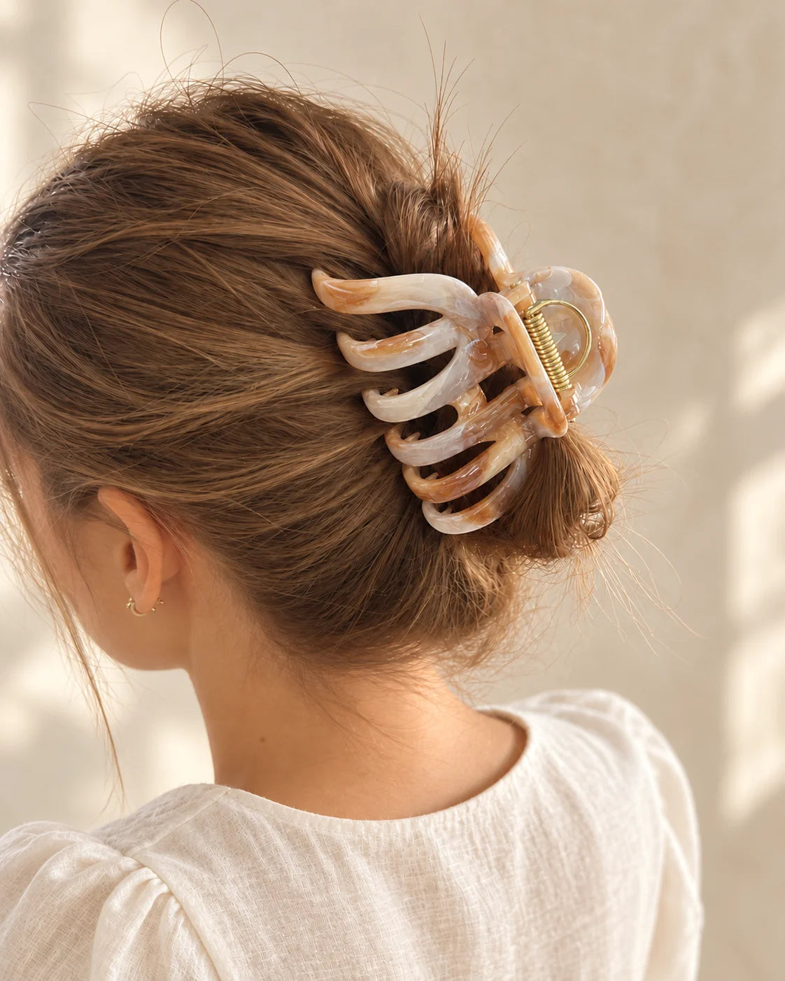Beige-braune Mira Haarkralle hält einen lockeren Dutt, von hinten fotografiert