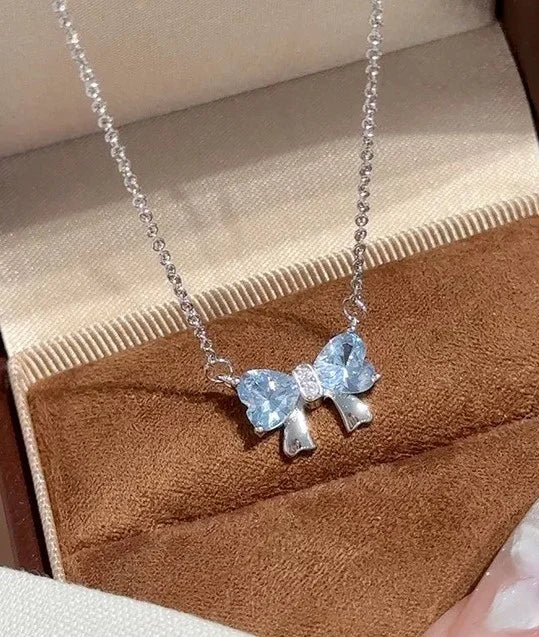 Silberne Halskette mit Anhänger in Schleifenform aus zwei blauen herzförmigen Steinen