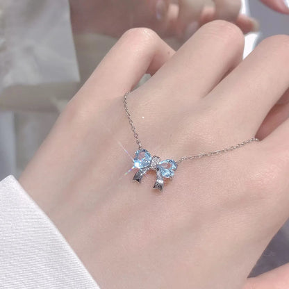 Silberne Halskette mit Anhänger in Schleifenform aus zwei blauen herzförmigen Steinen