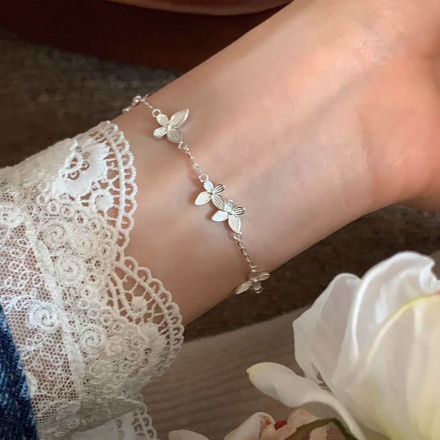 Versilbertes Armband mit gravierten Schmetterlingsblättern auf weißem Hintergrund.