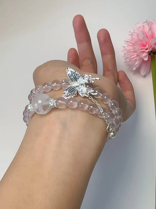 Rosa Rosenquarz-Perlenarmband mit Schmetterlingsanhänger – doppelt um den Finger gewickelt.