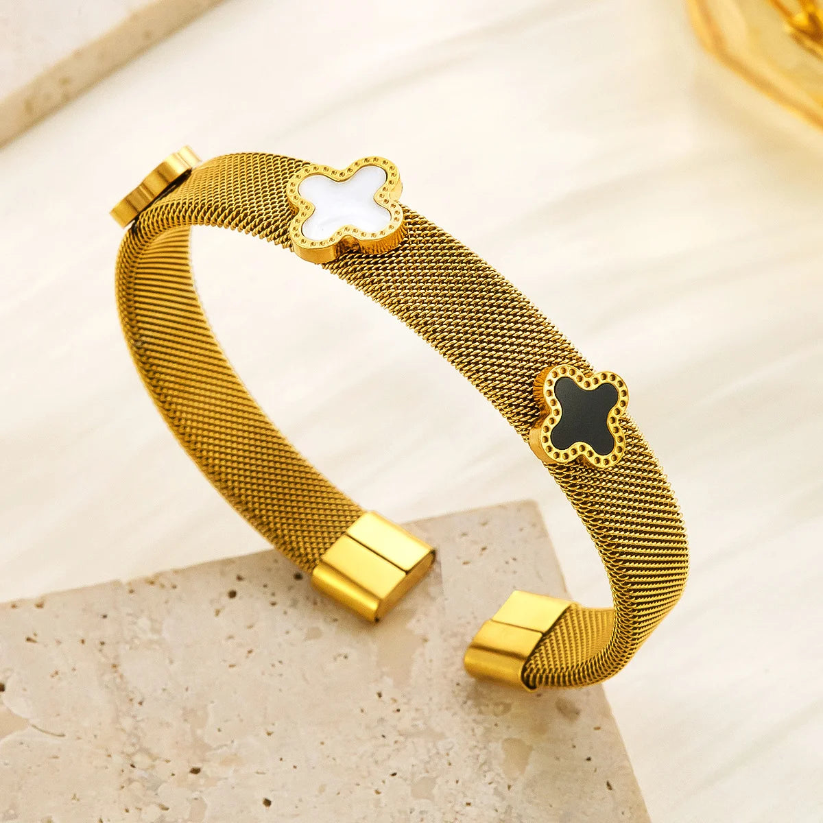 18k vergoldeter Mesh-Armreif "Siena" aus Edelstahl mit schwarzen und weißen Kleeblatt-Elementen
