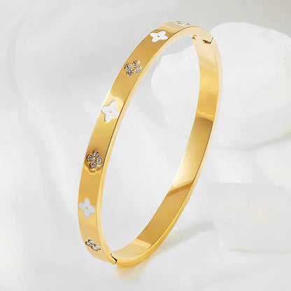 Vergoldeter Edelstahlarmreif mit weißen Blüten und Zirkoniasteinen