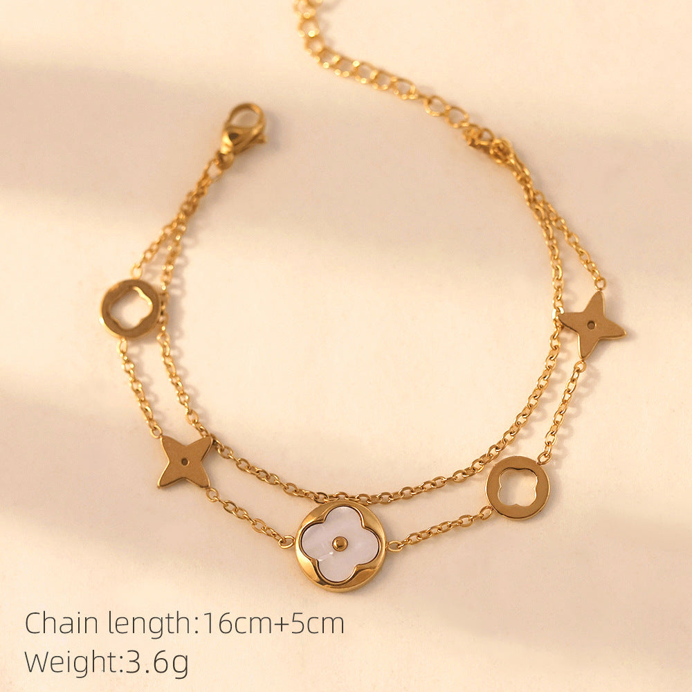 Vergoldete Doppelarmkette mit weißer Perlmuttblume und Symbolen