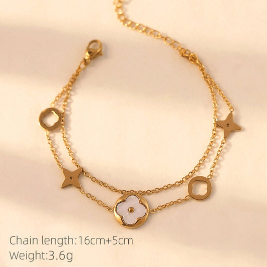 Vergoldete Doppelarmkette mit weißer Perlmuttblume und Symbolen