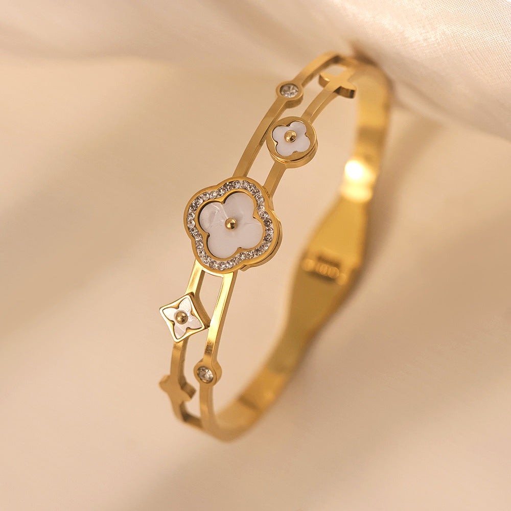 Vergoldeter Armreif mit weißen Perlmuttblüten und Zirkoniasteinen