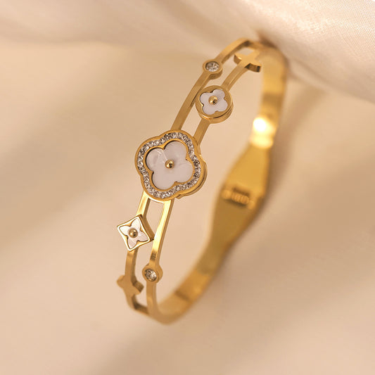 Vergoldeter Armreif mit weißen Perlmuttblüten und Zirkoniasteinen