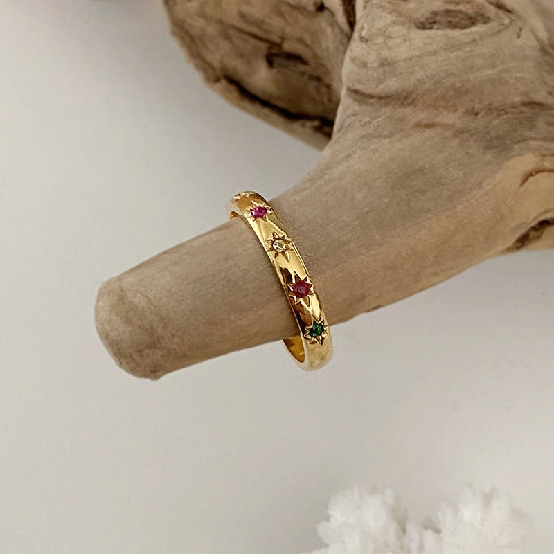 Zwei vergoldete Ringe mit bunten Steinen auf einem Finger – offenes Design, stapelbar.