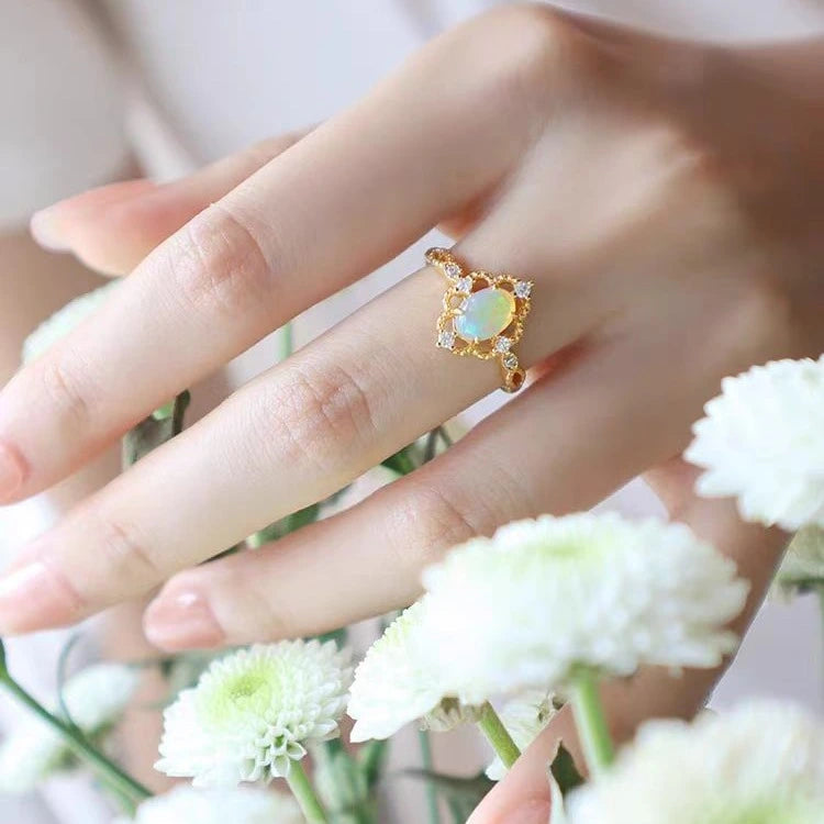 Verstellbarer vergoldeter Ring mit ovalem natürlichen Opal auf weiblicher Hand.