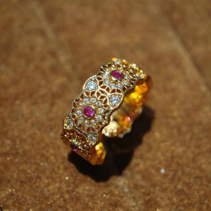 Breiter goldener Ring mit filigranem Muster und roten Steinen