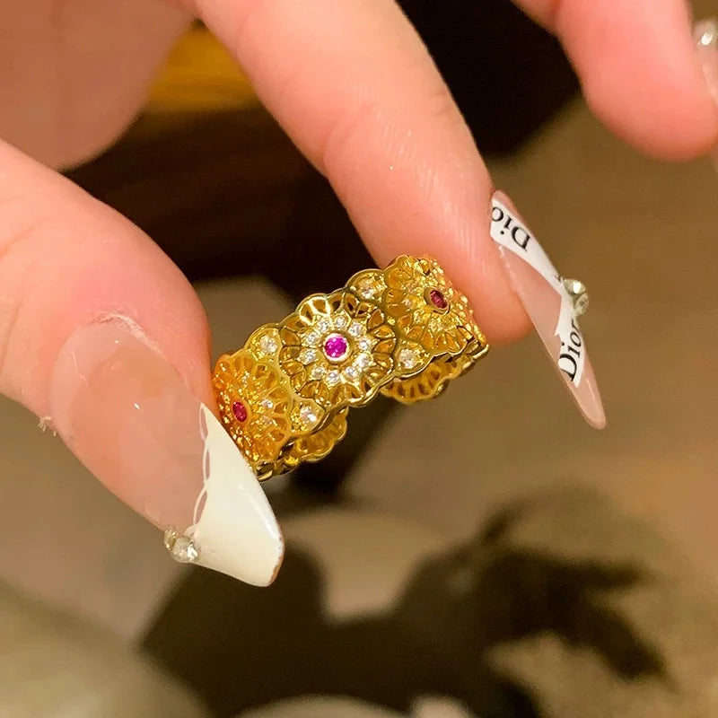 Breiter goldener Ring mit filigranem Muster und roten Steinen