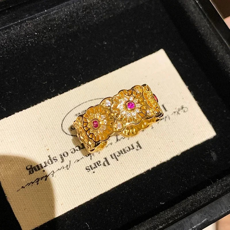 Breiter goldener Ring mit filigranem Muster und roten Steinen