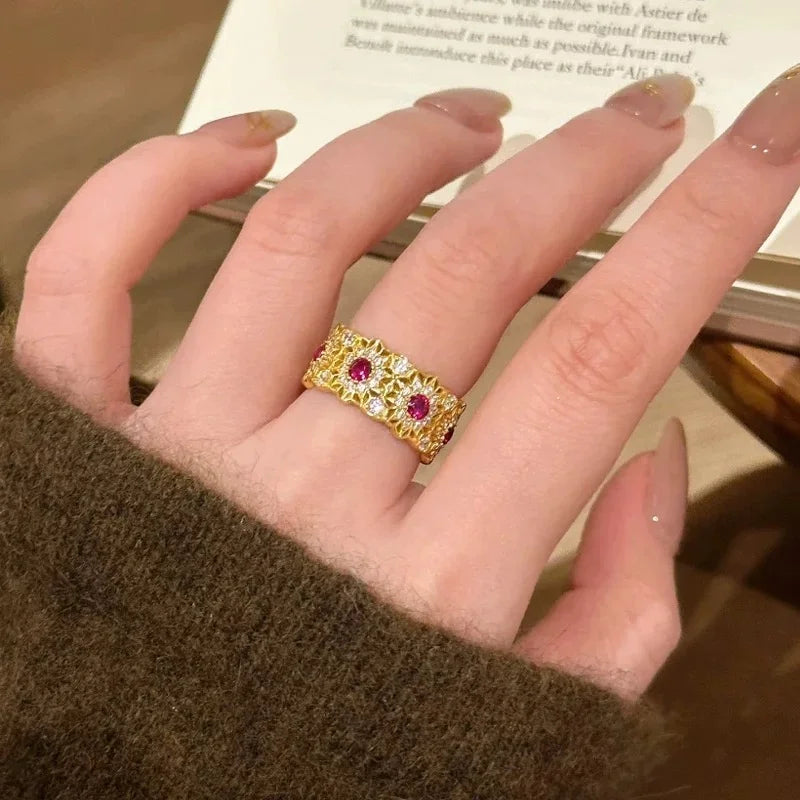Breiter goldener Ring mit filigranem Muster und roten Steinen