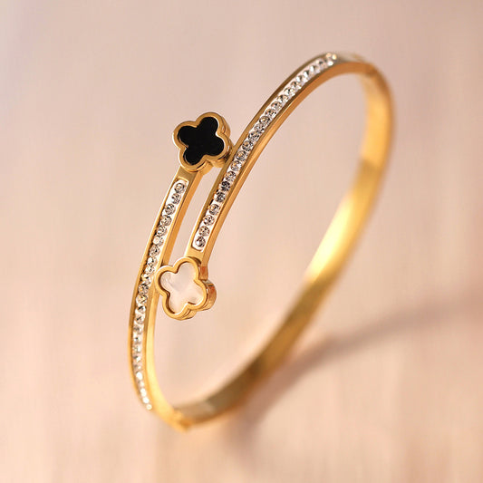 Vergoldeter Armreif mit schwarzen und weißen Kleeblatt-Elementen und Zirkonia