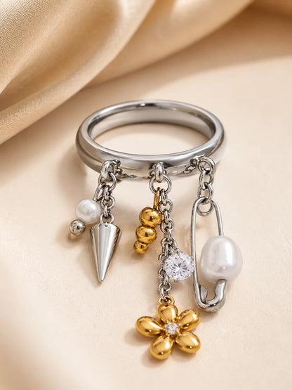 Silberner Ring aus Titanstahl mit verschiedenen baumelnden Charms wie einer Sicherheitsnadel, Perlen, einem Spike und einer 18K vergoldeten Blume