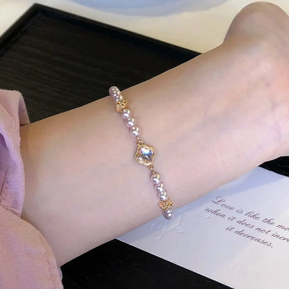 Elegantes Viona's Irisierendes Kleeblatt Armband aus rosig-weißen Kunstperlen mit goldenen Details und Glücksbringer-Anhänger
