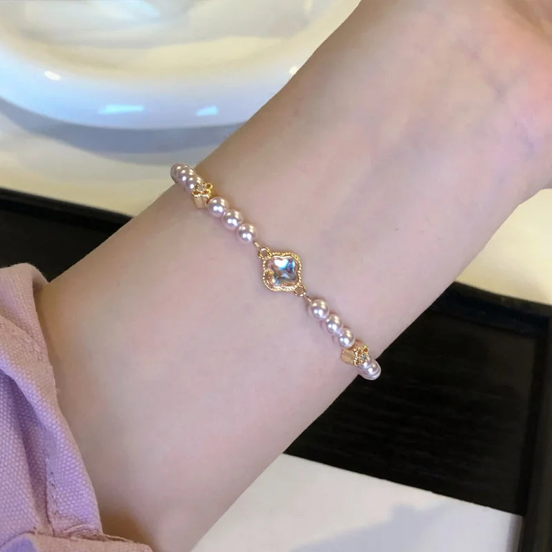 Elegantes Viona's Irisierendes Kleeblatt Armband aus rosig-weißen Kunstperlen mit goldenen Details und Glücksbringer-Anhänger