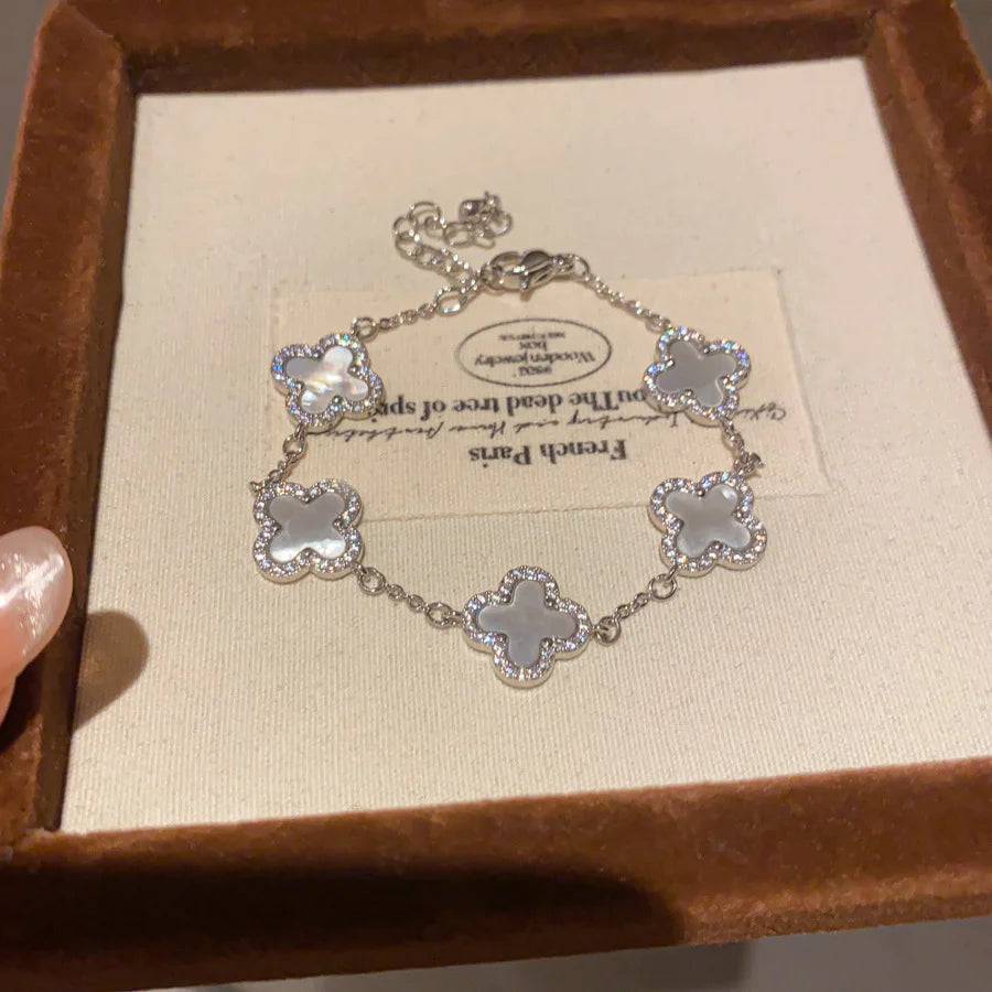 Elegantes versilbertes Armband mit fünf Kleeblatt-Motiven, verziert mit weißer Perlmutt-Optik und Zirkonia-Rand