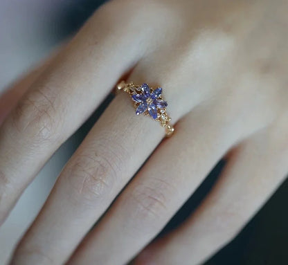 Goldener Ring mit lila Zirkonia Schneeflocke an einer Frauenhand