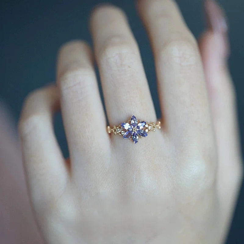 Goldener Ring mit lila Zirkonia Schneeflocke an einer Frauenhand