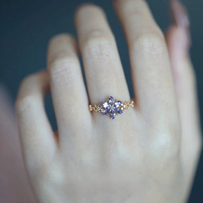 Goldener Ring mit lila Zirkonia Schneeflocke an einer Frauenhand