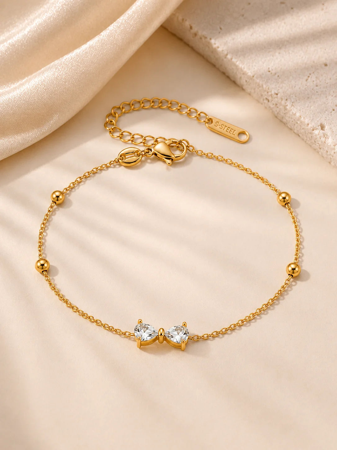 Zartes Zirkonia-Schleifen Armband aus 18K vergoldetem Titanstahl mit goldenen Perlen-Akzenten an der feinen Kette