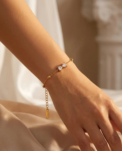Zartes Zirkonia-Schleifen Armband aus 18K vergoldetem Titanstahl mit goldenen Perlen-Akzenten an der feinen Kette