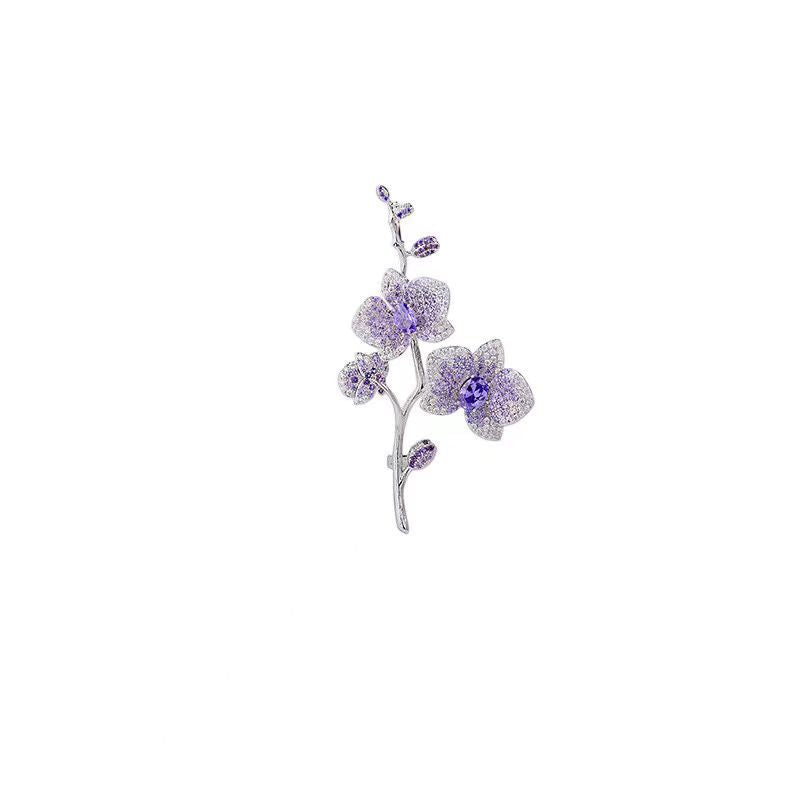 Elegante Orchideen-Brosche mit lila Zirkonia und Blütenmotiv auf silbernem Zweig