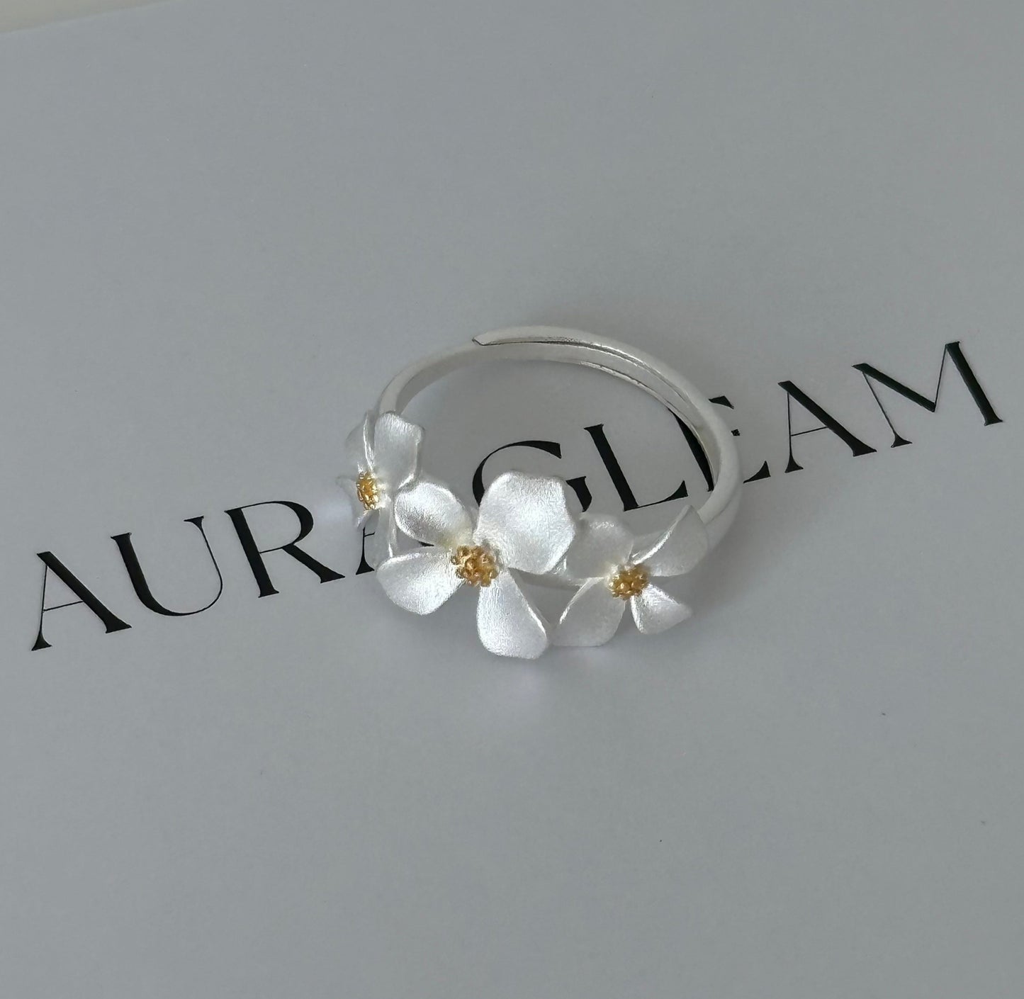 Verstellbarer Ring aus S999 Feinsilber mit drei zarten Gardenienblüten – florales Design mit goldfarbenem Blütenstempel für einen eleganten Naturlook