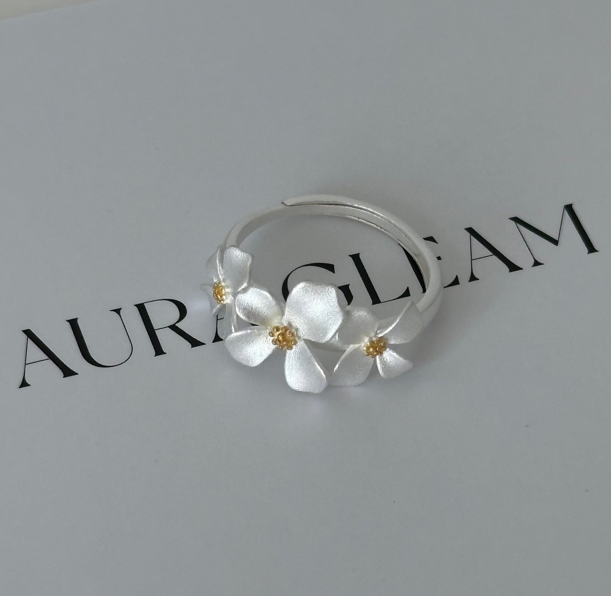 Verstellbarer Ring aus S999 Feinsilber mit drei zarten Gardenienblüten – florales Design mit goldfarbenem Blütenstempel für einen eleganten Naturlook